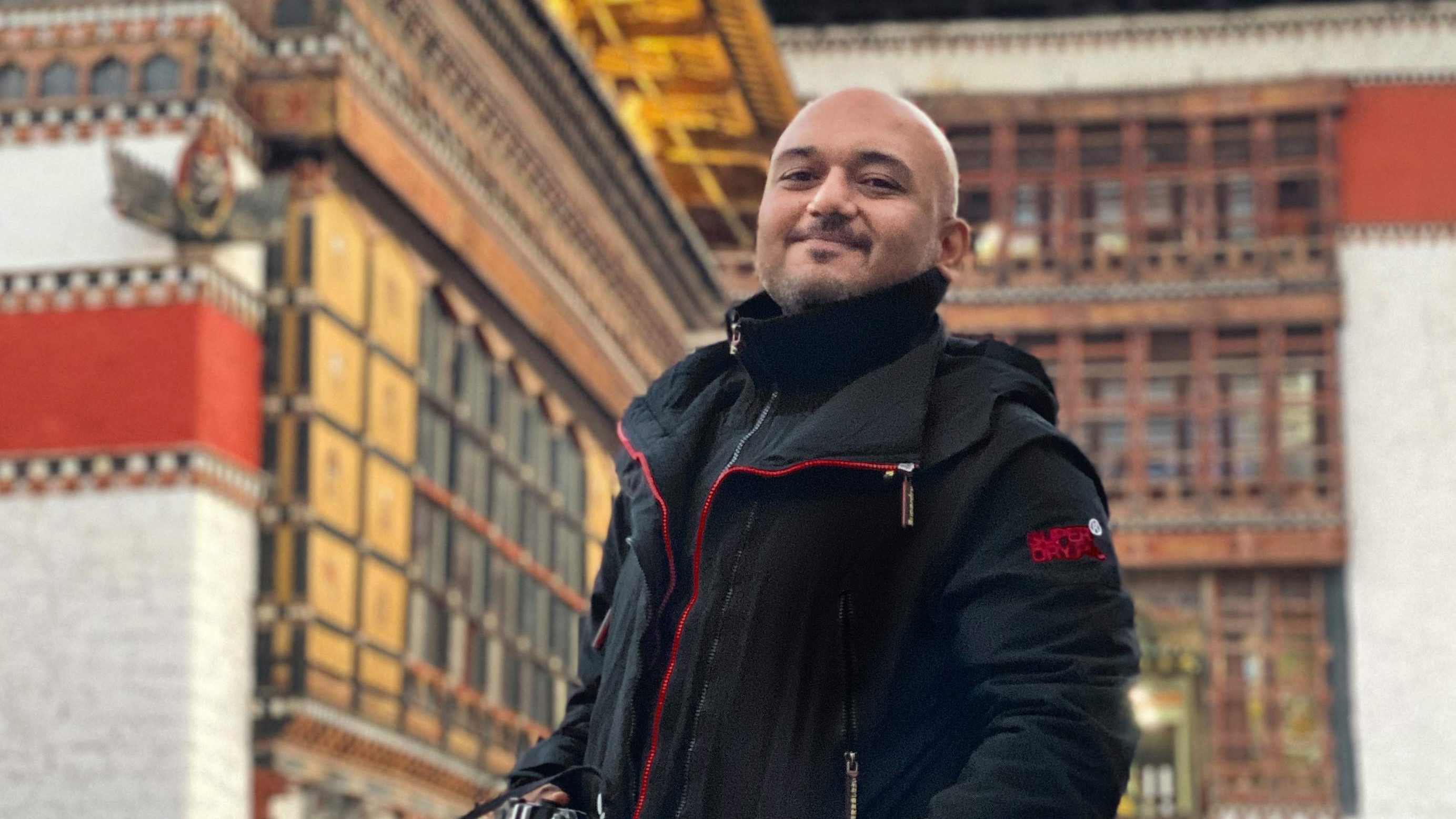 Vishal Bhanushali standing beside a traditional Himalayan building